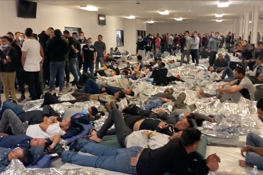 Migrants resting on the floor in an overcrowded center.