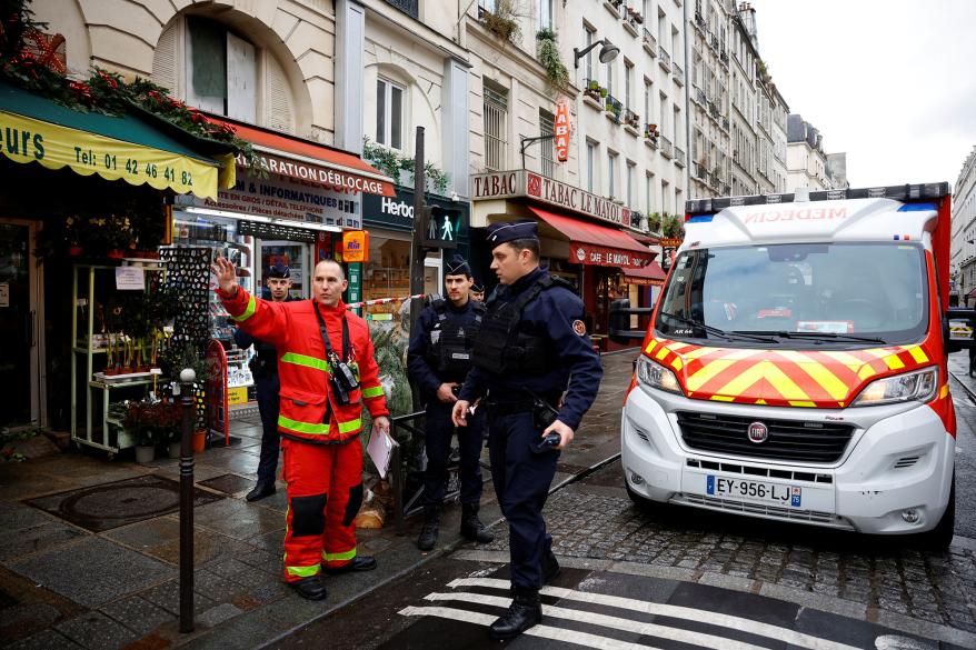 French police and firefighters secure a street after gunshots were fired killing two people and injuring several in a central district of Paris.