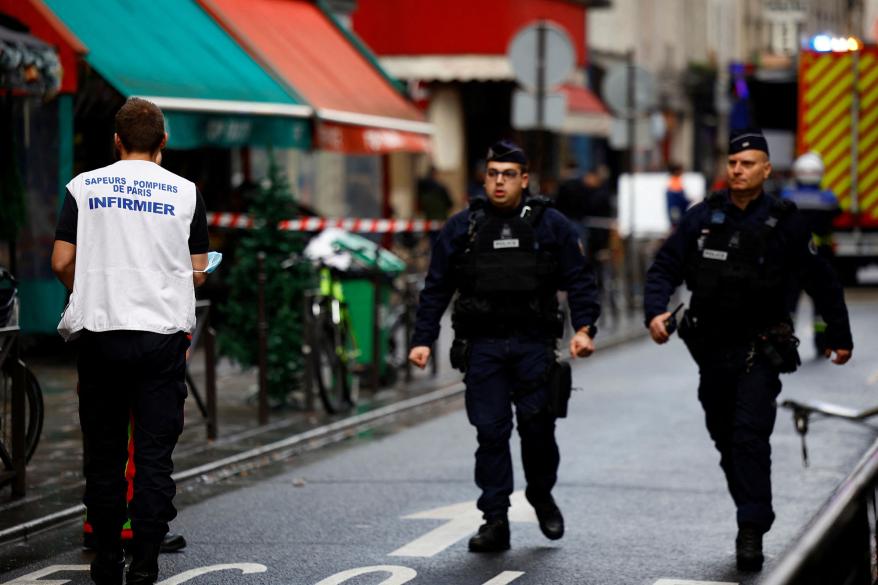 French police and firefighters secure a street after gunshots were fired killing two people and injuring several in a central district of Paris.