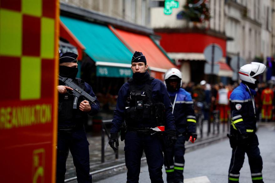 French police and firefighters secure a street after gunshots were fired killing two people and injuring several in a central district of Paris.