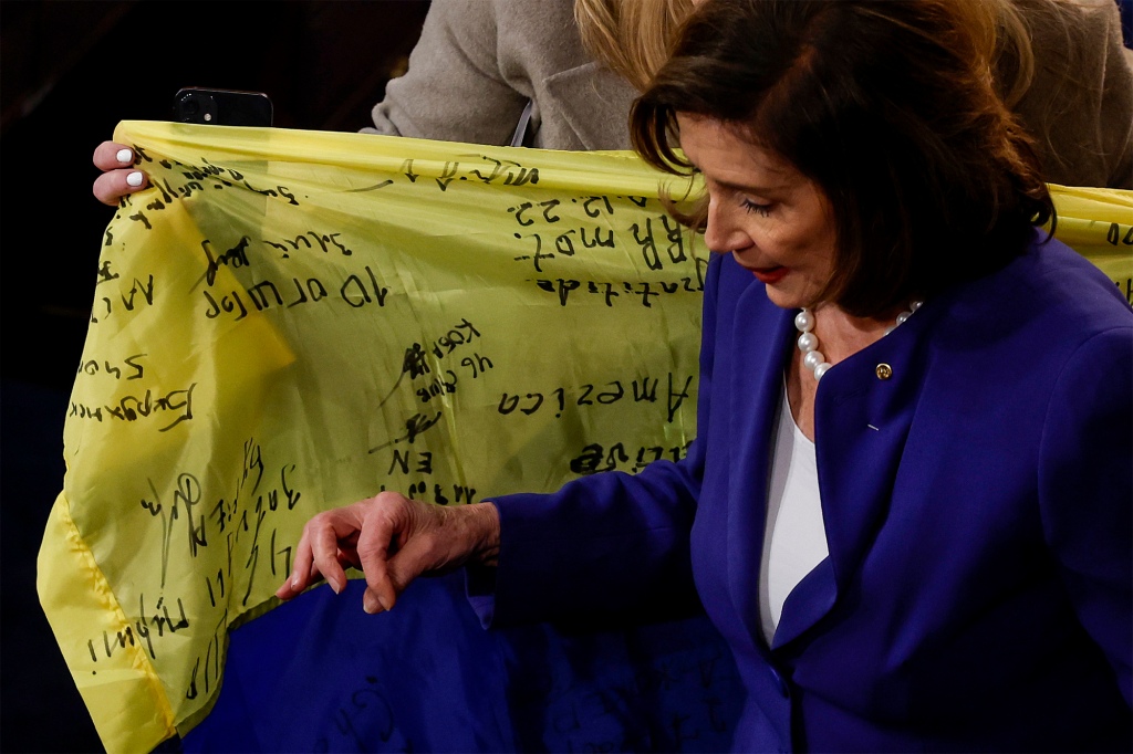 A staff member holds a Ukrainian flag, as Nancy Pelosi departs from a joint meeting of Congress in the House Chamber of the U.S. Capitol on Dec. 21, 2022 in Washington, DC.
