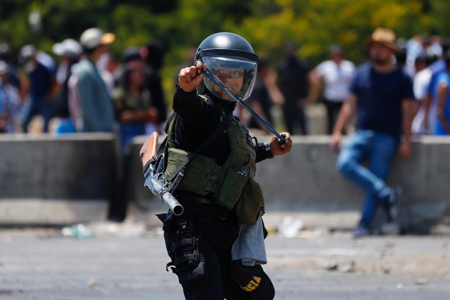 A riot police officer uses a sling shot against supporters of ousted Peruvian President Pedro Castillo