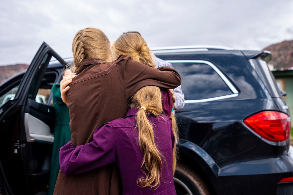 Three girls embrace before they are removed from the home of Samuel Bateman.