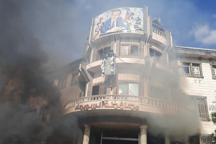 Smoke rises near a building as people take part in a protet.