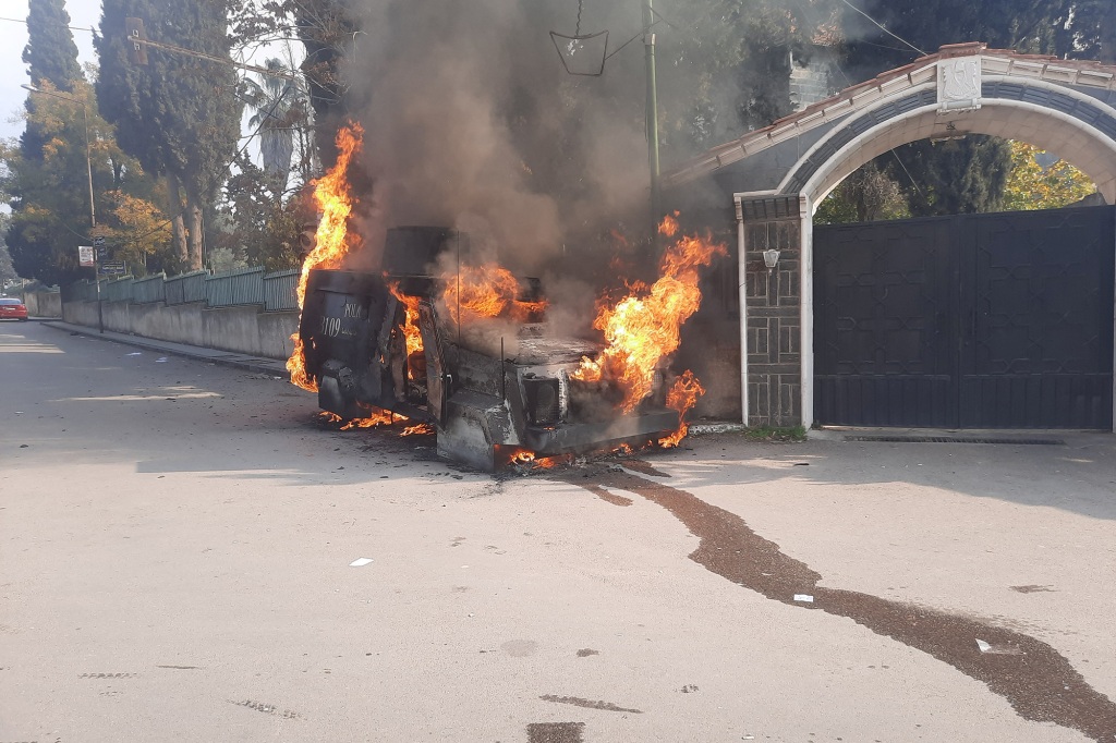 A police vehicle burns as people take part in a protest.