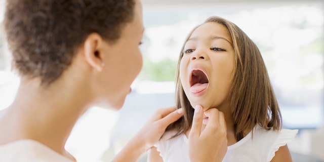 A woman checks her sick daughter's throat. "Serious viral infections like influenza A, RSV and COVID-19 all are a setup for secondary bacterial infections," said Dr. James H. Conway of Madison, Wisconsin.