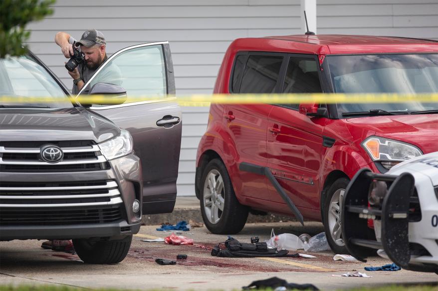 An investigator photographs a body inside a Toyota parked outside a Motel 6 in Bay St. Louis on Tuesday, Dec. 13, 2022. Police say a woman shot and killed two officers before killing herself. (Hannah Ruhoff/The Sun Herald via AP)