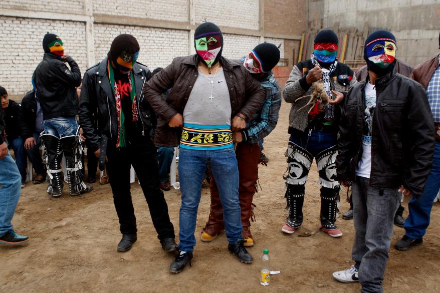 masked fighter Eber Sabina, center, is helped by friends with his outfit before entering a Takanakuy ritual fight in Lima, Peru.