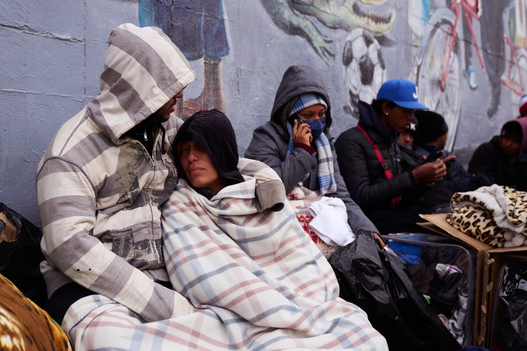 Migrants outside Sacred Heart Church after spending the night in the church gymnasium on Sunday, December 18, 2022 in El Paso, Texas. 