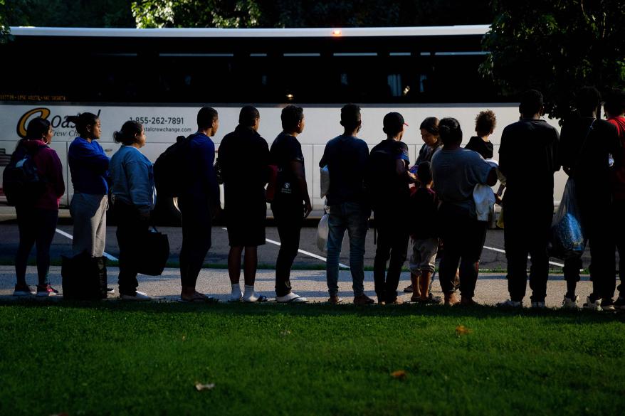 Migrants, who boarded a bus in Texas, listen to volunteers offering assistance after being dropped off within view of the US Capitol building in Washington, DC, on August 11, 2022.