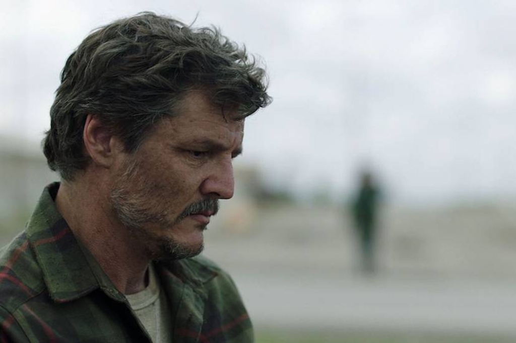 Pedro Pascal in "The Last of Us" standing outside looking pensive. 