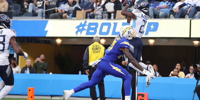 Roger McCreary #21 of the Tennessee Titans tips a pass intended for Mike Williams #81 of the Los Angeles Chargers to Joshua Kalu #28 of the Tennessee Titans for an interception during the second quarter at SoFi Stadium on December 18, 2022 in Inglewood, California.