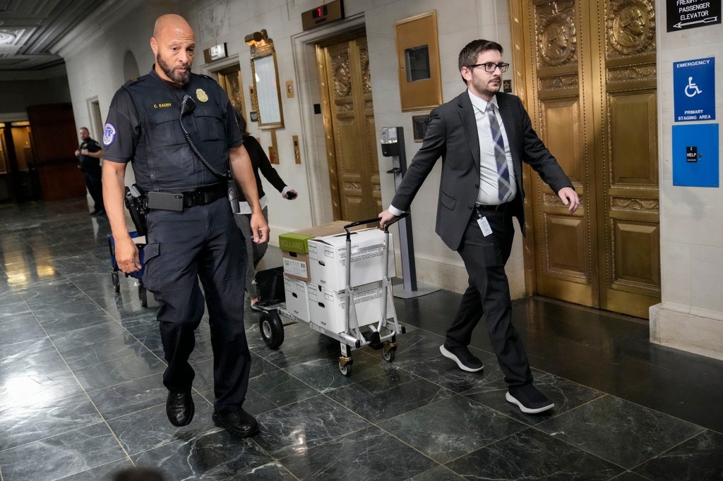 A picture of staff members move boxes of documents from the hearing room to the office of the House Ways and Means Committee.