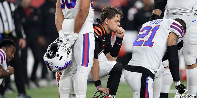 Joe Burrow of the Cincinnati Bengals, kneeling in center, and Jordan Poyer (21) of the Buffalo Bills react following the injury to Damar Hamlin during the first quarter at Paycor Stadium Jan. 2, 2023, in Cincinnati. 