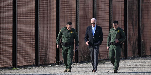 US President Joe Biden speaks with a member of the US Border Patrol as they walk along the US-Mexico border fence in El Paso, Texas, on January 8, 2023. 