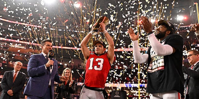 Quarterback Stetson Bennett #13 of the Georgia Bulldogs holds up the championship trophy after defeating the TCU Horned Frogs 65-7 to win the CFP National Championship Football game at SoFi Stadium in Inglewood on Monday, January 9, 2023. 