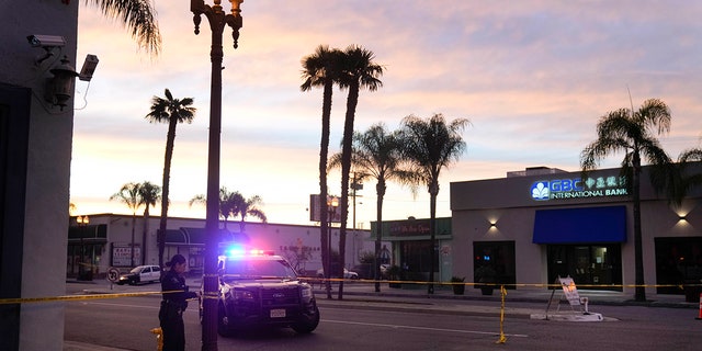 A police officer ties tape around a light pole in Monterey Park, California, Sunday, Jan. 22, 2023. A mass shooting took place at a dance club following a Lunar New Year celebration, setting off a manhunt for the suspect.