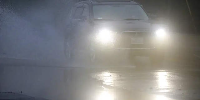 An automobile drives through a flooded portion of Mountain Boulevard in Oakland, Calif. Rain is expected across the Bay Area this week.