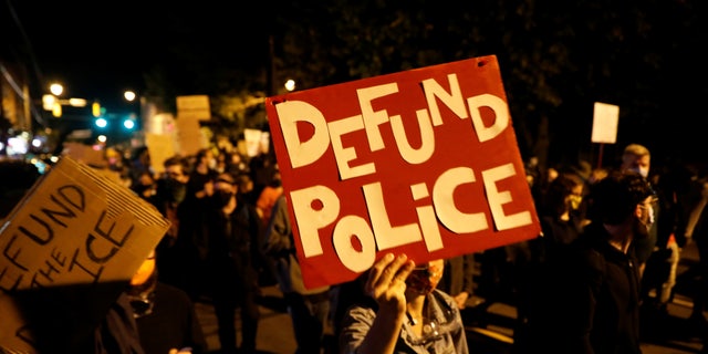 Demonstrators hold a sign saying "defund the police" during a protest over the death of a Black man, Daniel Prude, after police put a spit hood over his head during an arrest in Rochester, N.Y., Sept. 6, 2020.