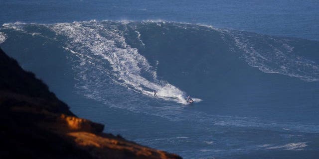 A surfer is towed-in, in Praia do Norte, Nazare, Portugal, January 8, 2022. REUTERS/Pedro Nunes