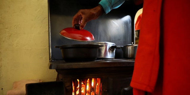 Pinkie Sebitlo cooks using a coal stove during frequent power outages from South African utility Eskom, caused by its aging coal-fired plants, in Soweto, South Africa, June 23, 2022.