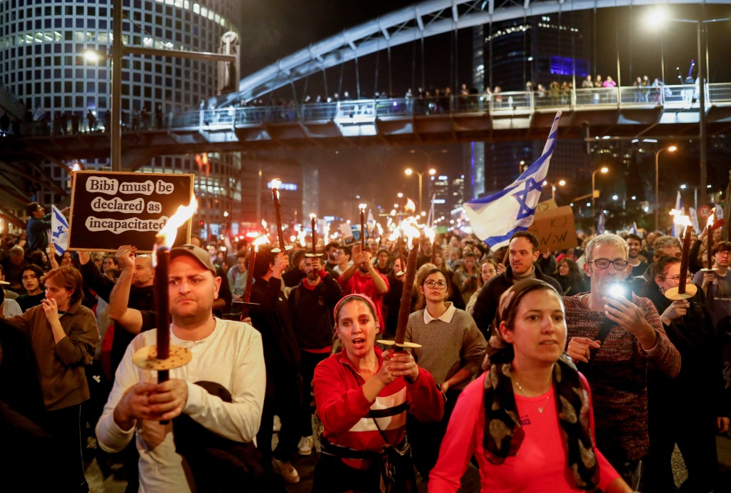 Protesters carry candles and signs during Saturday's demonstrations in Tel Aviv, Israel.