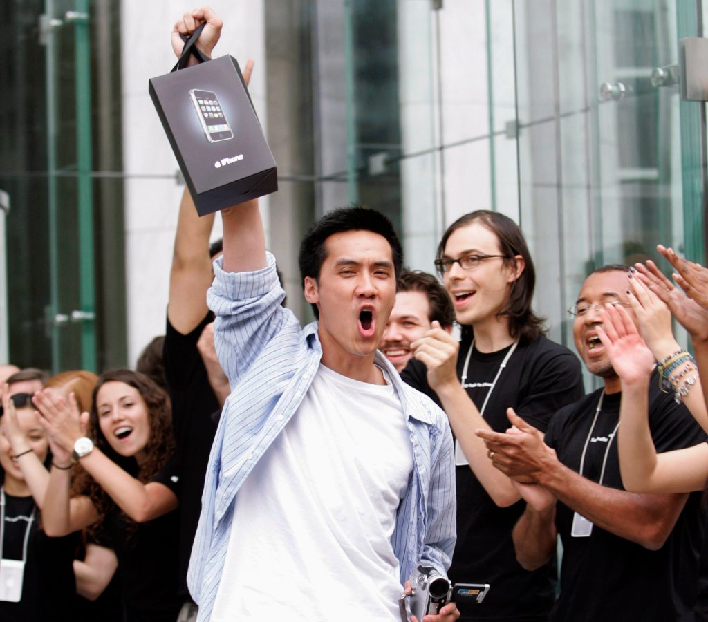 Surrounded by cheering Apple Store employees, one of the first iPhone buyers leaves the store on Fifth Avenue in New York, June 29, 2007.  