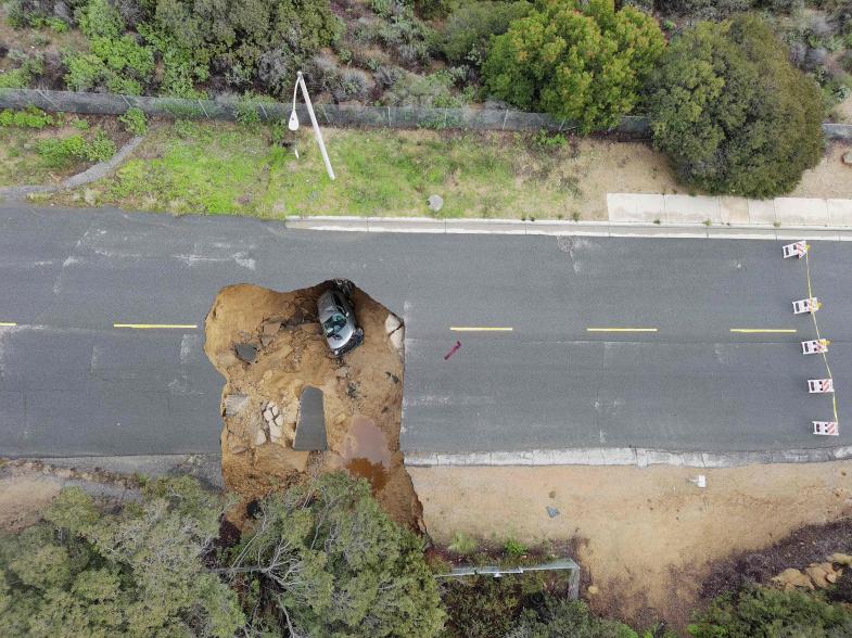 This aerial view shows two cars siting in a large sinkhole that opened during a day of relentless rain on Jan. 10, 2023 in Los Angeles, Calif.