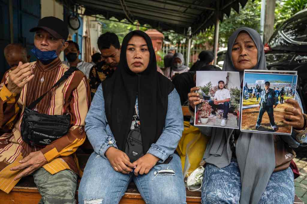 A woman holds up pictures of her late son who died in the October 1, 2022 Kanjuruhan football stadium disaster.