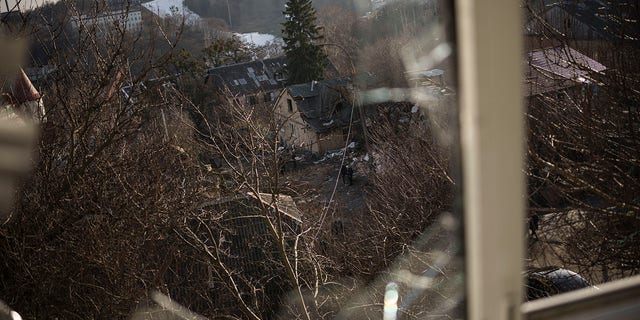 Damaged houses are seen through a broken window, following a Russian attack on New Year's Eve, in Kyiv, Ukraine, Monday, Jan. 2, 2023. 