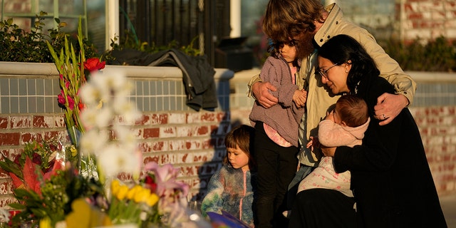 A family gathers at a memorial outside the Star Ballroom Dance Studio on Tuesday, Jan. 24, 2023, in Monterey Park, Calif. A gunman killed multiple people at the ballroom dance studio late Saturday amid Lunar New Years celebrations in the predominantly Asian American community. 