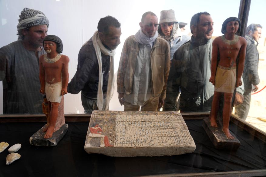 Egyptian antiquities workers watch recently discovered artifacts at the site of the Step Pyramid of Djoser.