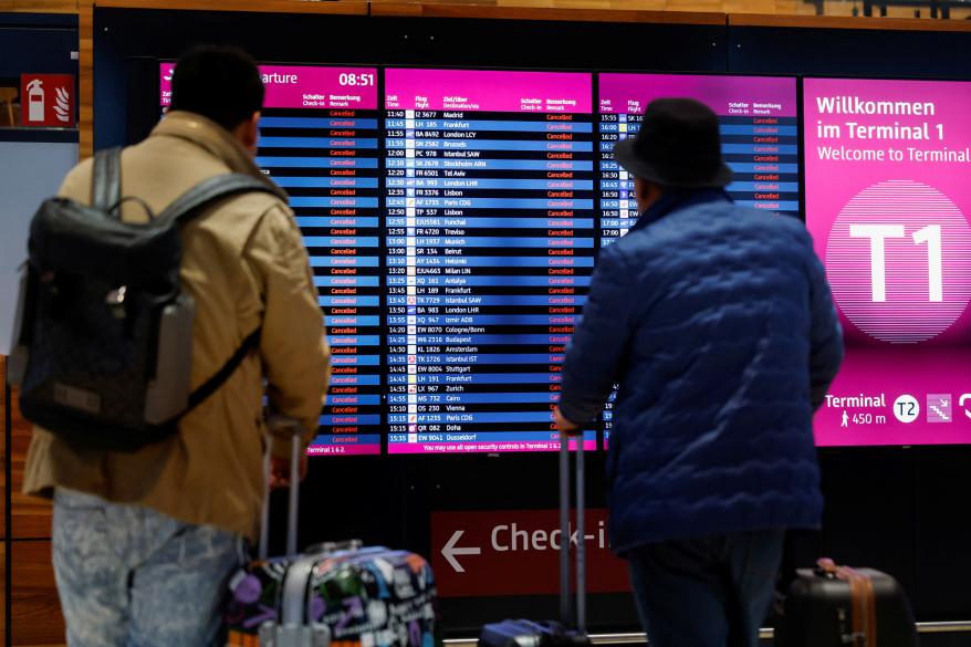 Passengers look at departure panels showing canceled flights during a general strike by employees over pay demands, at the Berlin Brandenburg Airport (BER), in Schoenefeld near Berlin on Jan. 25, 2023.