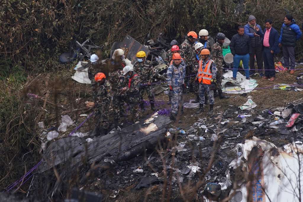 Rescuers scour the crash site in the wreckage.