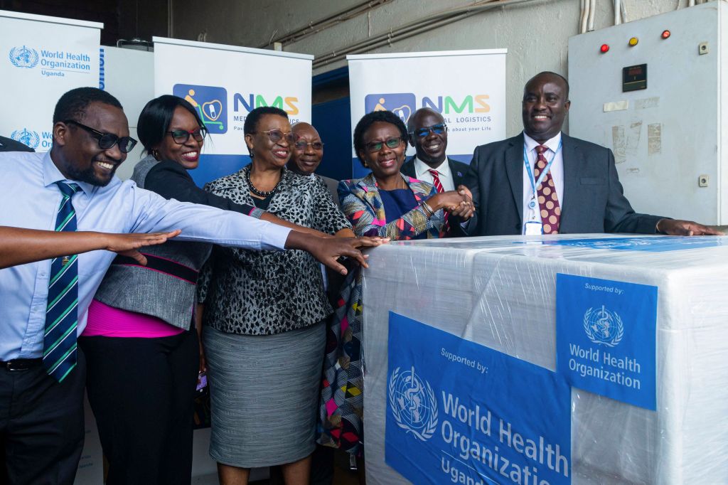 Charles Njuguna (right), Incident Manager for the World Health Organization Country Office in Uganda, and Uganda's Health Minister Jane Ruth Aceng (third right) pose after receiving 1200 doses of Ebola trial vaccine at National Medical Stores. 