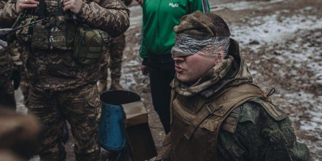 DONETSK, UKRAINE - JANUARY 12: Ukrainian soldiers frisk a Russian soldier captured on the Donbas frontline in Donetsk, Ukraine on January 12, 2023. 