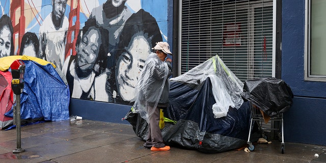 Homeless tents and a homeless woman are seen near the Tenderloin District during rainy day in San Francisco on January 13, 2023, as atmospheric river storms hit California, United States. 