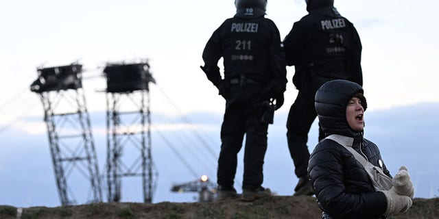 Climate activist Greta Thunberg stands between Keyenberg and Lützerath under police guard on the edge of the open pit mine. 