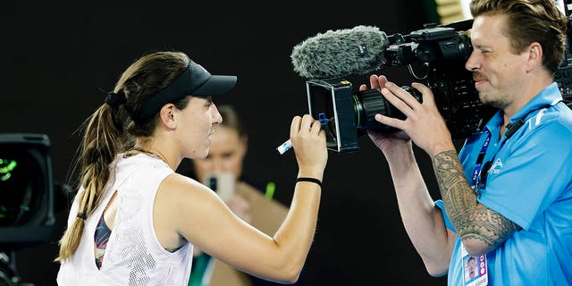 Jessica Pegula signs on the camera lens. 