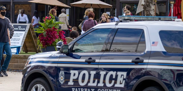 This file images shows a police car is parked outside as people visit  Mosaic Shopping Center Mall on October 30, 2021 in Fairfax Virginia. 