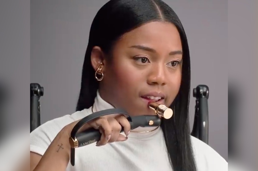 A woman tests out Lancome's handheld lipstick applicator for people with limited hand and arm mobility.