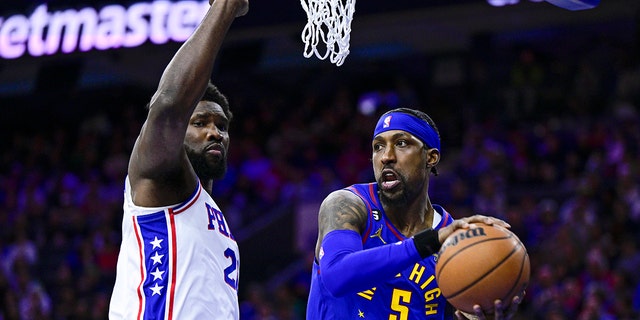 Denver Nuggets' Kentavious Caldwell-Pope passes the ball as Philadelphia 76ers' Joel Embiid defends, Saturday, Jan. 28, 2023, in Philadelphia.