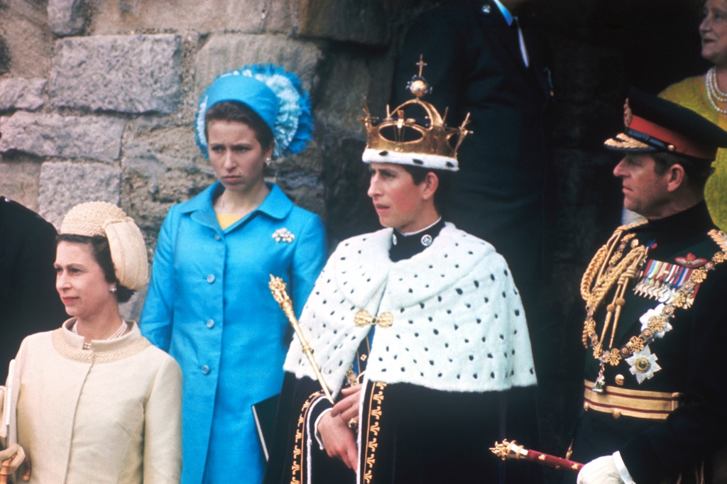 (Original Caption) Prince Charles stands on castle steps after being invested as Prince of Wales. He is flanked by his mother, Queen Elizabeth II, and father, Prince Philip. Behind them is Queen Mother Elizabeth.