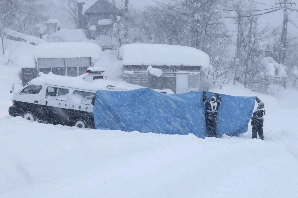 Police officers try to transport victims found at an accident site following an avalanche in Japan. 