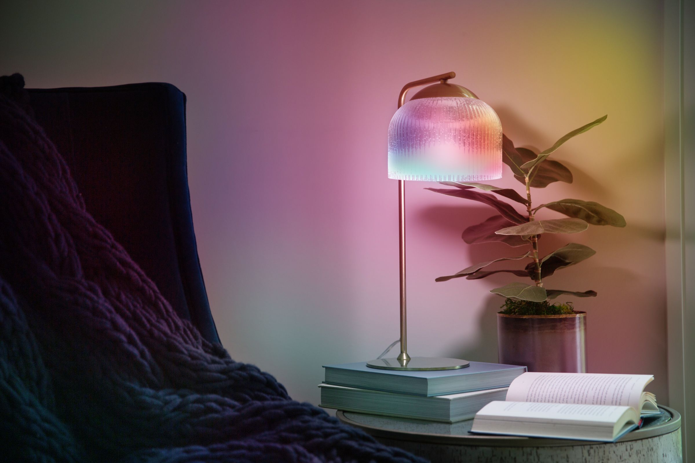 A lamp showing multiple colors on a table next to a wall.