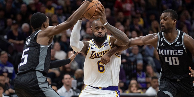 Kings guard De'Aaron Fox, left, and forward Harrison Barnes defend against Los Angeles Lakers forward LeBron James in Sacramento, Saturday, Jan. 7, 2023.