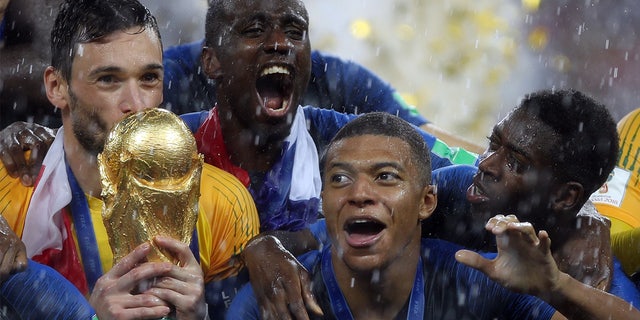 Hugo Lloris surrounded by his France teammates and holding the World Cup trophy after besting Croatia at the Luzhniki Stadium in Moscow on July 15, 2018. 