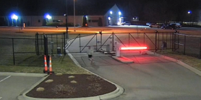 One of the inmates is seen jogging in the parking lot of a nearby business before a car is stolen, police say, while the other is crawling under the fence to enter the lot.