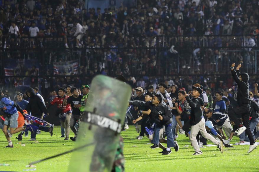 Soccer fans rush the pitch during a clash between supporters at Kanjuruhan Stadium in Malang, Indonesia.