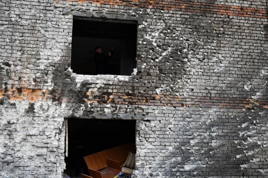 A local resident is seen in a window hole of an apartment building damaged in the night following a Russian rocket attack in Zaporizhzhya.